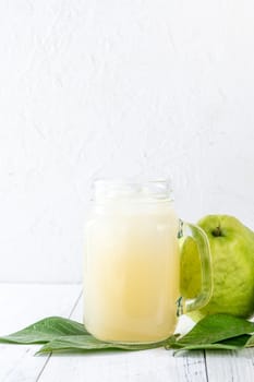 Delicious beautiful guava fruit with fresh juice set isolated on bright white wooden table background, close up.