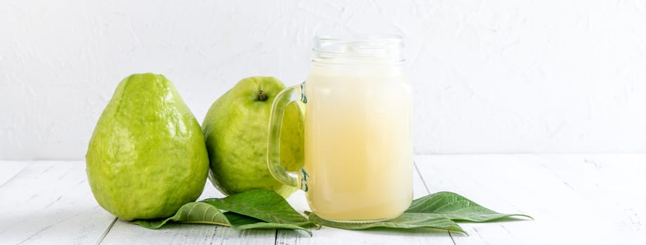 Delicious beautiful guava fruit with fresh juice set isolated on bright white wooden table background, close up.