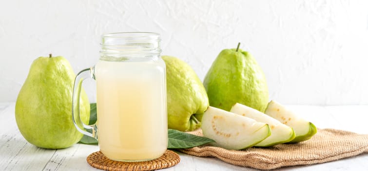 Delicious beautiful guava fruit with fresh juice set isolated on bright white wooden table background, close up.