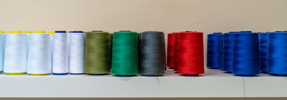 colored threads for the sewing machine on the shelf, banner.