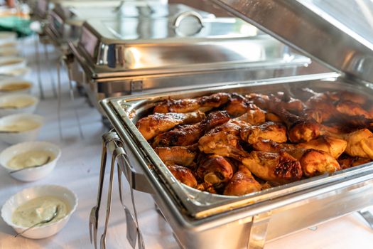roast chicken thighs in a warming pot on a catering table.