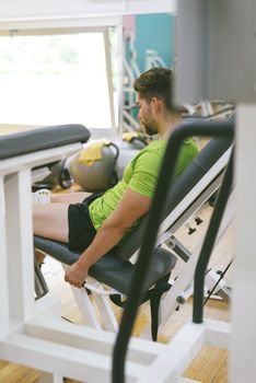 Young sportsman almost shouting when doing leg extension with heavy weight