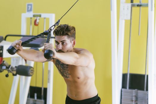 Fit man on lat pull down machine at the health club. Work out on Pull down Weight Machine