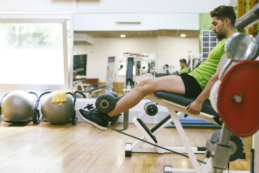 Young sportsman almost shouting when doing leg extension with heavy weight