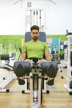 Young sportsman almost shouting when doing leg extension with heavy weight