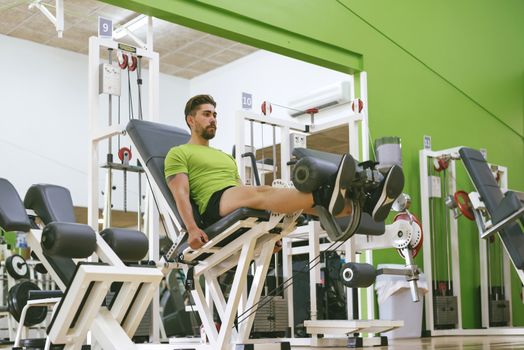 Young sportsman almost shouting when doing leg extension with heavy weight