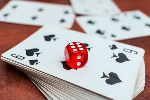 Red dice lie on a deck of playing cards in a casino. Casino gambling with dice and cards