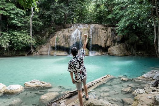 Man standing on the stone at Erawan waterfall at National Park, Kanchanaburi, Thailand.
