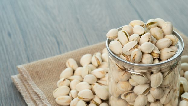 Pistachio nuts in transparent glass jar on a wooden table. Healthy food high protein.