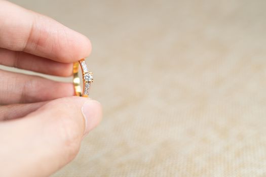 Man holding wedding ring over brown sack background.