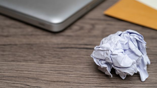Crumpled balls of white paper in hand over wooden table, workspace.