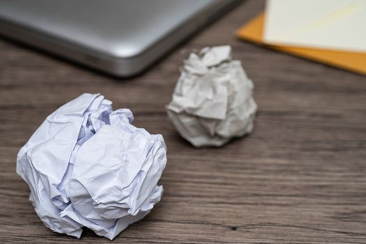 Crumpled balls of white paper on wooden table, workspace.