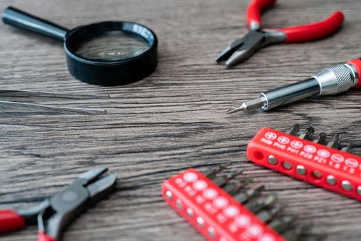 Tools collection : Set of heads screwdrivers, pliers and a magnifying glass on wooden table.