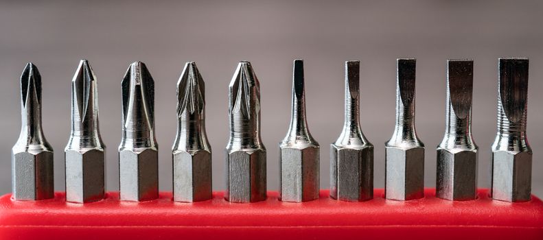 Set of heads for screwdriver, tools collection on red table.