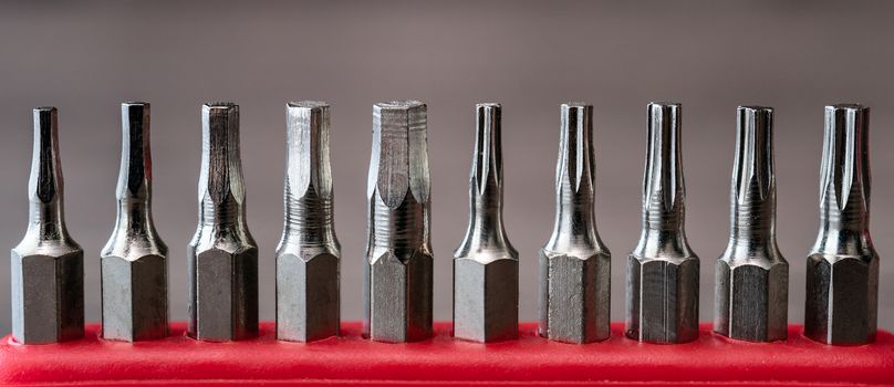 Set of heads for screwdriver, tools collection on red table.