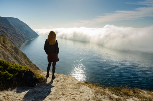 A girl stands on a hill and observes an unusual phenomenon of nature over the sea