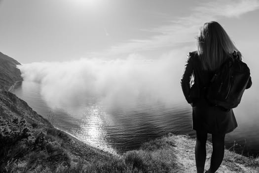 Girl watching from the mountain for the fog over the sea, black and white photography