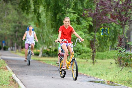 Girl and mom ride a bike along the alley