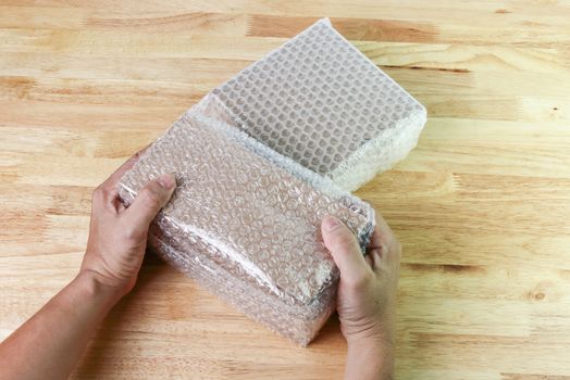 hand of man hold Bubbles covering the box by bubble wrap for protection product cracked  or insurance During transit - 
