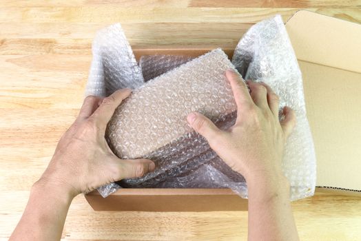 hand of man hold Bubbles covering the box by bubble wrap for protection product cracked  or insurance During transit  
