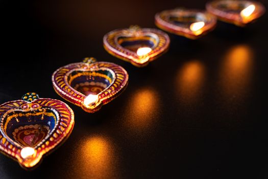 Indian festival Diwali, Diya oil lamps lit on colorful rangoli. Hindu traditional. Happy Deepavali. Copy space for text.