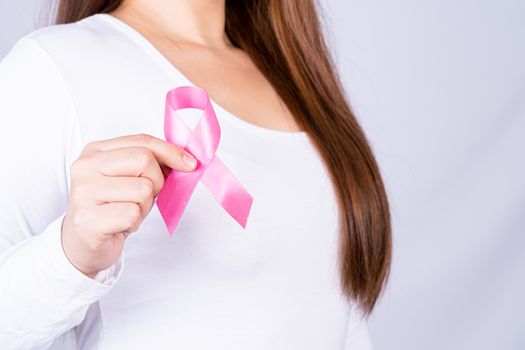 Breast cancer awareness ribbon on woman chest on grey background. Medical, healthcare for advertising concept.