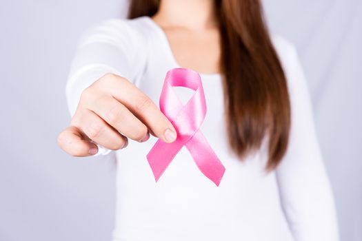 Breast cancer awareness ribbon on woman chest on grey background. Medical, healthcare for advertising concept.