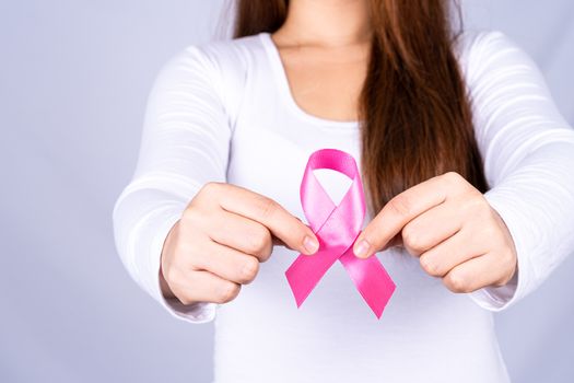 Breast cancer awareness ribbon on woman chest on grey background. Medical, healthcare for advertising concept.