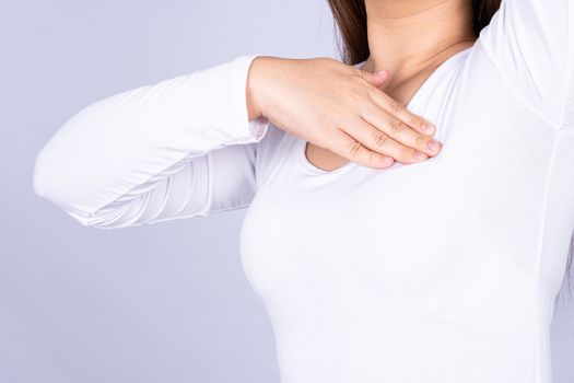 Woman hands doing breast self exam for checking lumps and signs of breast cancer on grey background. Medical, healthcare for advertising concept.