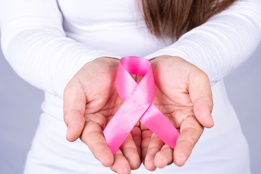 Woman hands holding pink breast cancer awareness ribbon. Medical, healthcare for advertising concept.