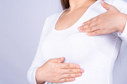 Woman hands doing breast self exam for checking lumps and signs of breast cancer on grey background. Medical, healthcare for advertising concept.