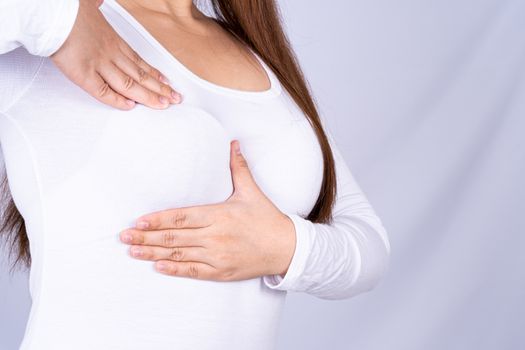 Woman hands doing breast self exam for checking lumps and signs of breast cancer on grey background. Medical, healthcare for advertising concept.