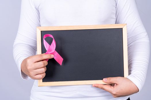 Breast cancer awareness ribbon on blackboard holding by woman. Medical, healthcare for advertising concept.