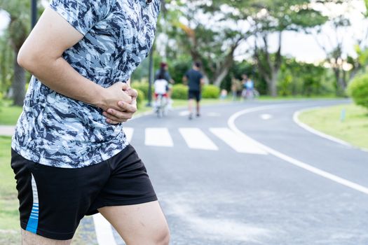 Asian man suffering from stomach ache while running at the park. Injury from sport and exercise concept.