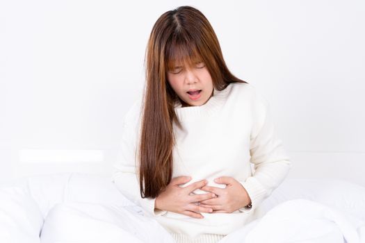 Young woman suffering stomach aches lying on the bed. Healthcare medical or daily life concept.