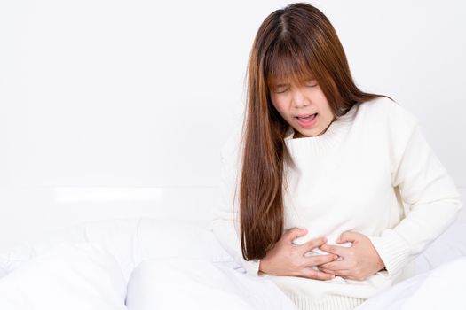 Young woman suffering stomach aches lying on the bed. Healthcare medical or daily life concept.