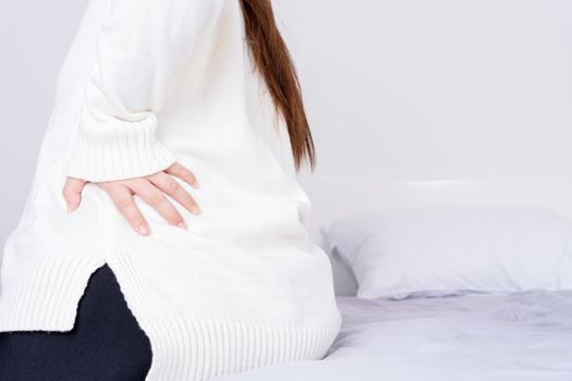 Young woman suffering back pain from uncomfortable bed. Healthcare medical or daily life concept.