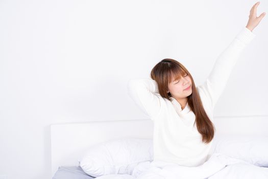 Young Asian woman stretching in bed after wake up from the good comfortable bed. Healthcare medical or daily life concept.