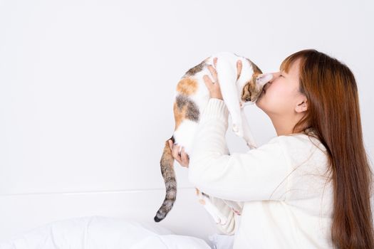 Woman at home holding and kissing her lovely fluffy cat. Multicolor tabby cute kitten. Pets and lifestyle concept.