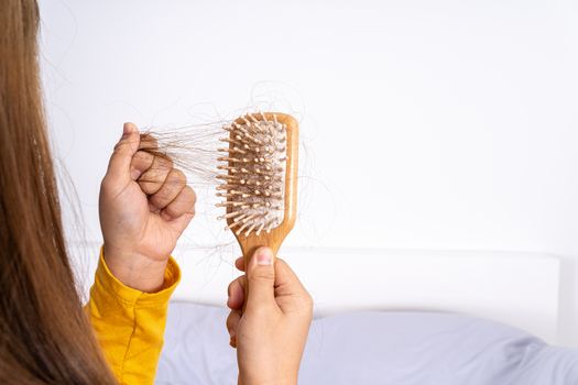 Hair fall problem, closeup hand holding comb and problem hair. Healthcare medical or daily life concept.