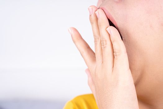 Asian woman are yawning covering open mouth with hand after she wake up. Healthcare medical or daily life concept.