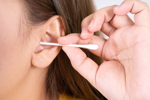 woman cleaning her ear with a cotton swab. A woman suffered an infection after using the sticks incorrectly.