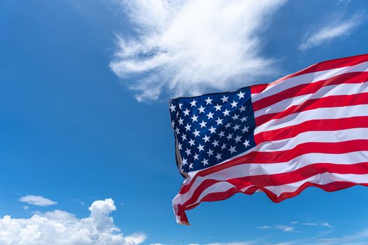 Waving USA flag under blue sky background.