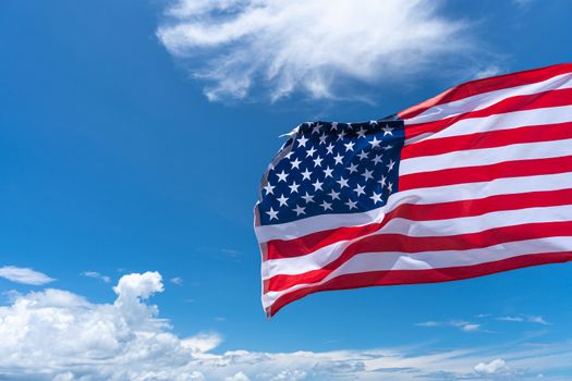 Waving USA flag under blue sky background.