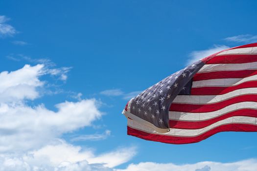 Waving USA flag under blue sky background.