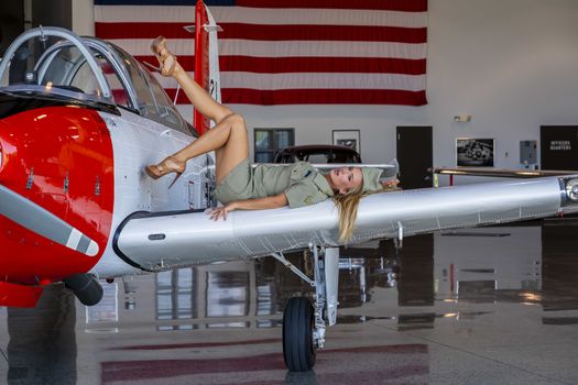 A beautiful blonde model poses with a vintage WWII aircraft