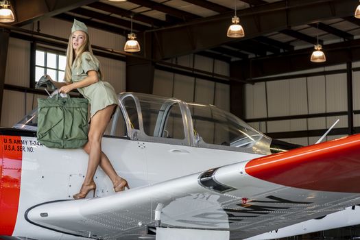 A beautiful blonde model poses with a vintage WWII aircraft