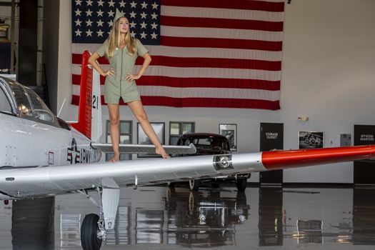 A beautiful blonde model poses with a vintage WWII aircraft