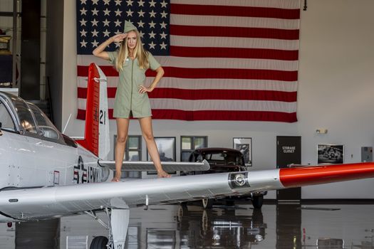 A beautiful blonde model poses with a vintage WWII aircraft