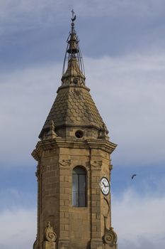 Ayerbe, Spain - October 15, 2020: Ayerbe clock tower and bell tower, in Gothic and Baroque style, located in the Plaza de Ramon y Cajal, near the palace of the Marquises of Urries.